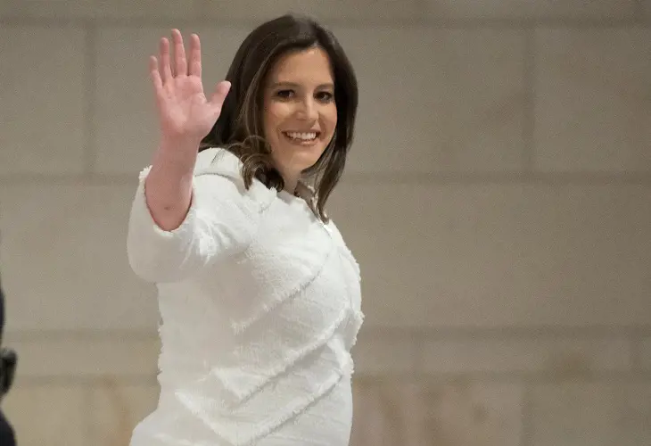 Elise Stefanik wearing a white dress and waving her hands during her pregnancy.